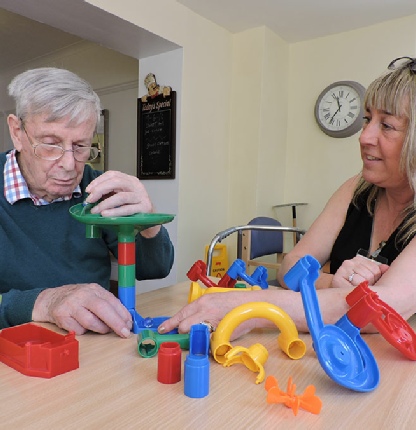 Plactic building shapes on table showing with Support Staff showing activities in Care Home